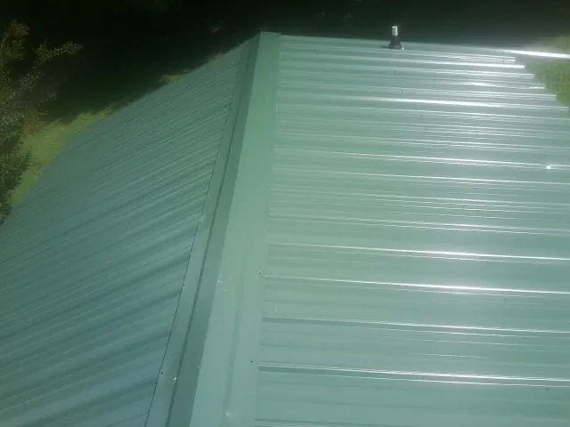 New green metal panels meeting at the ridge of a roof — Flat Roof Repair work by our crew in Fairchild Air Force Base