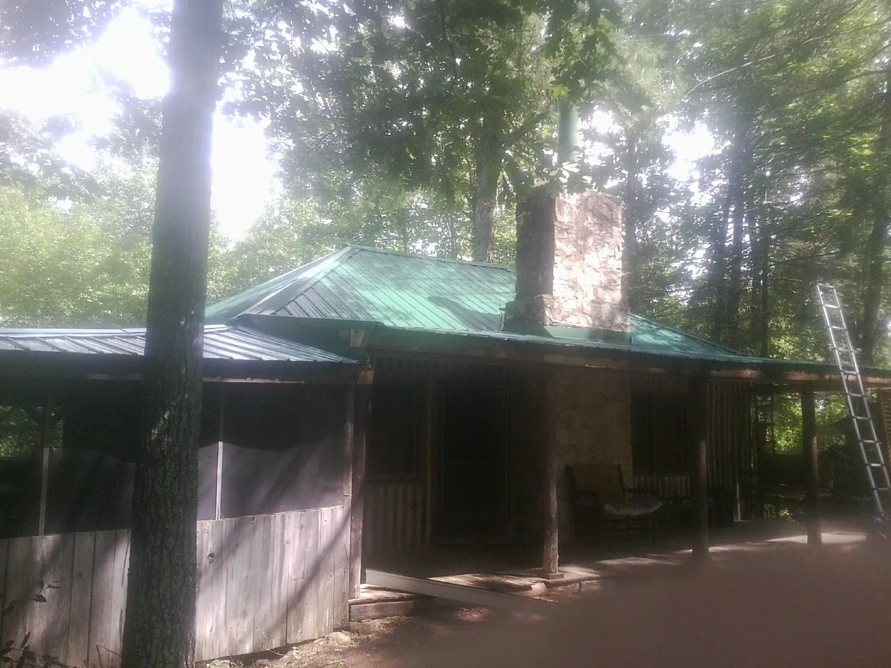Green metal roof and stone chimney above a log cabin porch in Fairchild Air Force Base