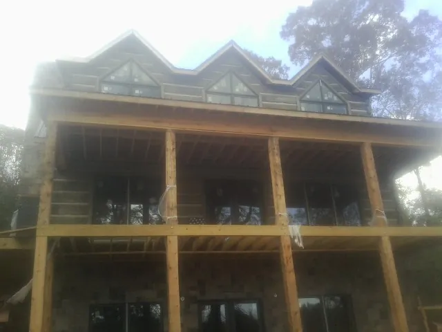 Dormers and porch framing on a large log home under construction — Roof Coating work by our crew in Fairchild Air Force Base