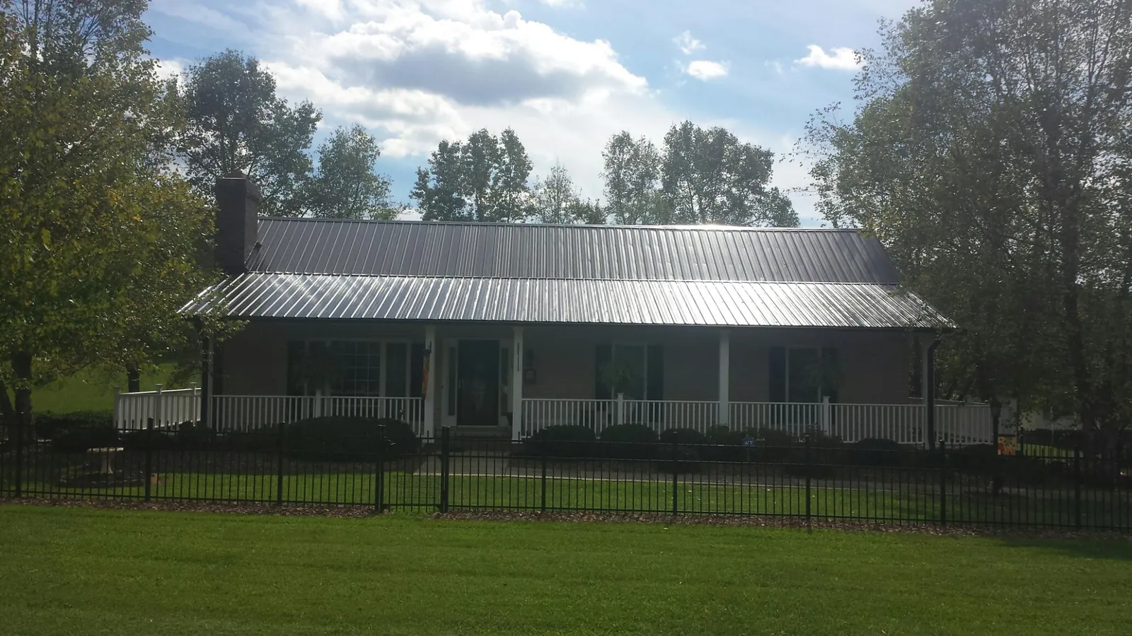 Gray metal roof on a brick ranch with a full width front porch — Gutter Guard Installation work by our crew in Fairchild Air Force Base
