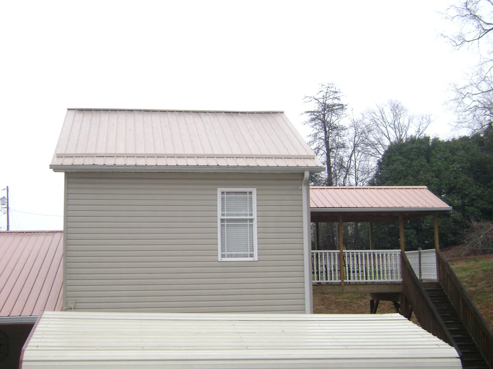 Tan metal roofs on a two story addition and attached porch, from a Roof Replacement job in Fairchild Air Force Base