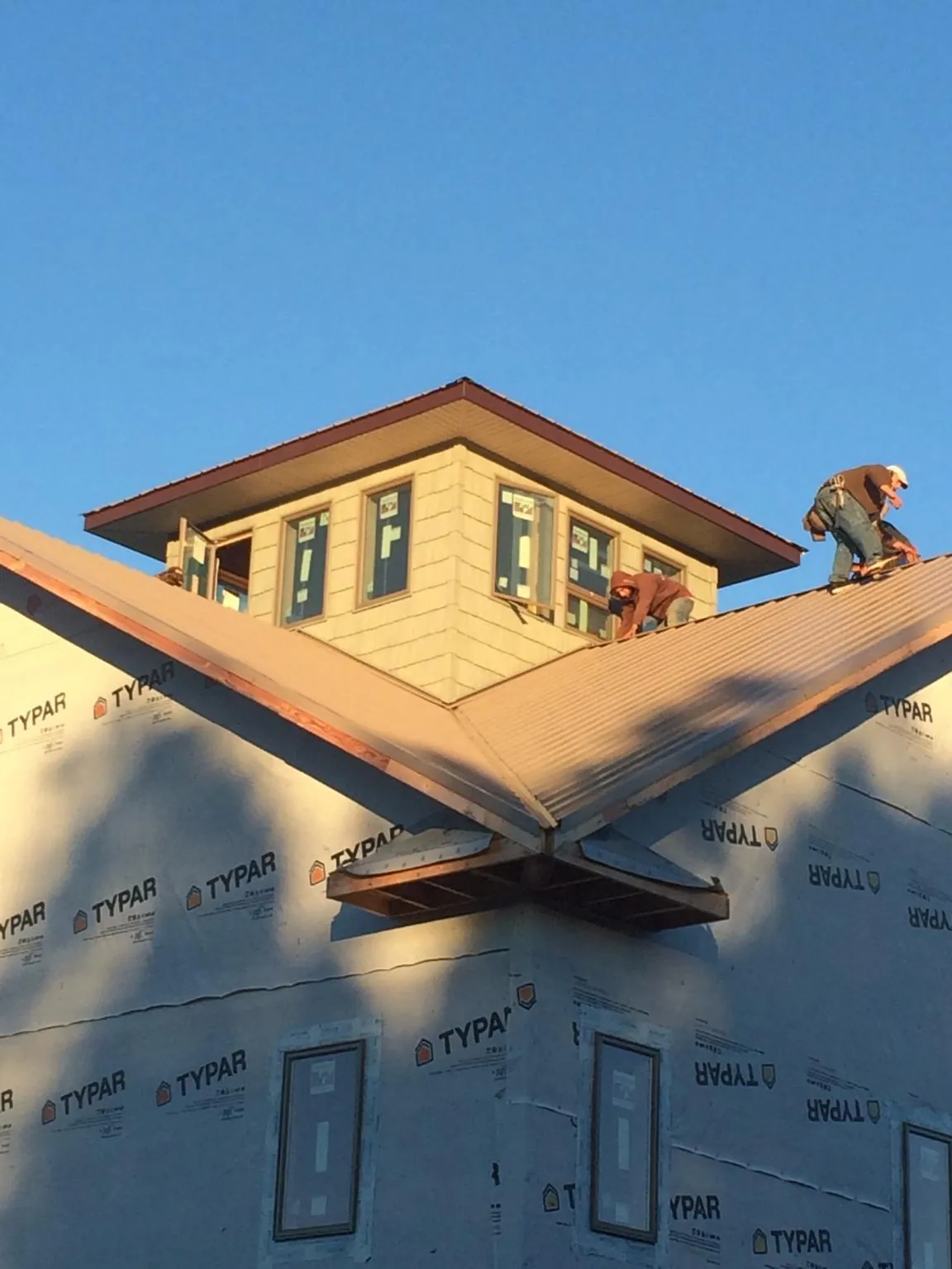 Roofers working around a rooftop cupola on a new metal roof at sunset — Roof Waterproofing in Fairchild Air Force Base by Roofing Brothers